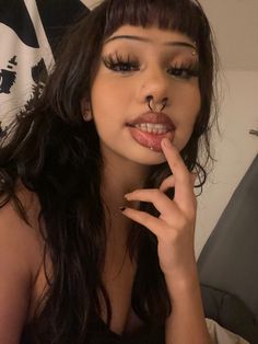 a woman with her finger on her lips and nose piercing in front of the camera