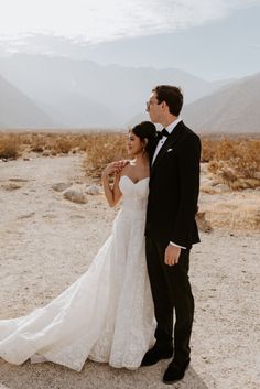 a bride and groom standing in the desert