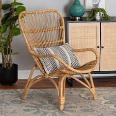 a wicker chair sitting on top of a rug next to a potted plant