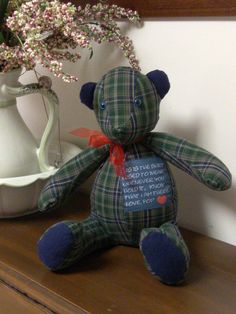 a teddy bear sitting on top of a wooden table next to a vase with flowers