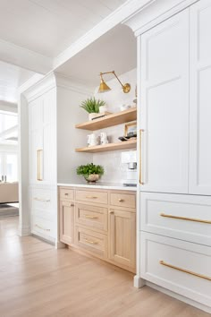 a kitchen with white cabinets and wood flooring in the center, along with open shelving