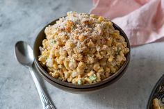 a bowl filled with macaroni and cheese on top of a table next to a spoon