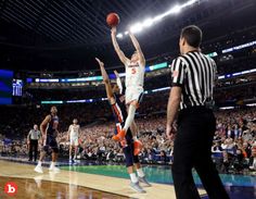 a basketball player is jumping up to dunk the ball in front of an official