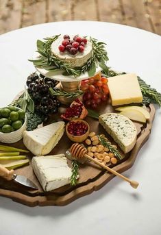 an assortment of cheeses and fruits on a platter