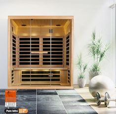 a large wooden sauna in a white room with black tile flooring and potted plants