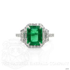 an emerald and diamond ring with two side stones