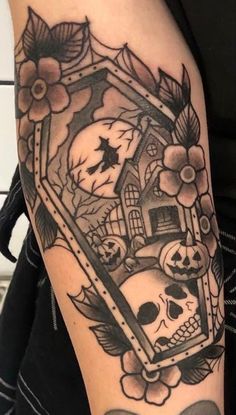 a tattoo with skulls and flowers on the arm, in front of a mirror that has an image of a house