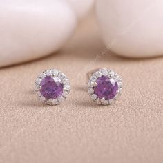 Amethyst Purple Stud Earring | Purple & White Moissanite Diamond Earring in 925 Sterling Silver | Gemstone Earring | Sapphire Stud Earrings These gorgeous gemstone earrings are a brilliant gift-giving choice for February birthdays and anniversaries. Ornate round-cut amethysts deliver standout style when sweetly embraced with bright round-cut white lab-created sapphires. Fashioned in stylish sterling silver. Earring Details: 1. No of Earrings - 1 Pair  2. Metal Color - Silver  3. Metal Type - 925 Fine Jewelry Purple Halo Jewelry, Purple Diamond Jewelry With Halo Design, Purple Halo Jewelry As A Gift, Purple Gemstones With Prong Setting, Lavender Amethyst Round Earrings, Gift Amethyst Jewelry With Halo Design, Elegant Purple Birthstone Gemstones, Formal Purple Round Earrings, Purple Cubic Zirconia Jewelry With Halo Setting