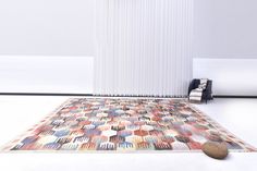 a room with a rug on the floor and a chair next to it in front of a white wall