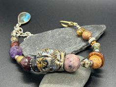 This earthy polymer-textured handmade bead was fun to make, I painted it with gold and silver colors with the black showing through.  This is unique and bohemian in style.  I added a chain for adjusting the length.  The sterling silver charm dangles off the end of the bracelet is a labradorite charm.  This bracelet measures  a size 7.5-8.75 inches in long. Artsy Adjustable Gold Bracelets, Artsy Adjustable Gold Bracelet, Adjustable Artsy Gold Bracelet, Artisan Beaded Bracelets For Festivals With Unique Variations, Eclectic Handmade Gold Bracelets, Eclectic Handmade Gold Bracelet, Handmade Artsy Gold Bracelets, One Of A Kind Bohemian Beaded Bracelets For Festival, One-of-a-kind Bohemian Beaded Bracelets For Festivals