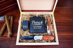 an open box containing several personal items on a wooden table next to some cigars