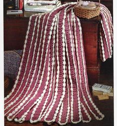 a crocheted blanket sitting on top of a table next to a book shelf