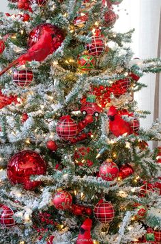 a christmas tree decorated with red and green ornaments, birds ornament balls and tinsel