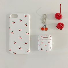 an apple, cherries and cell phone case sitting next to each other on a white surface