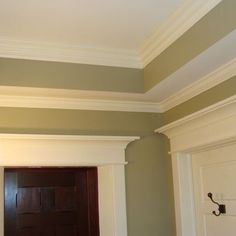 an empty room with a wooden door and white trim on the walls, along with green paint