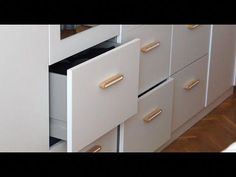 an open drawer in a white cabinet with gold handles