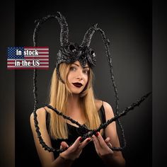 a woman wearing a spider costume and holding her hands in front of her face with the words in stock in the u s