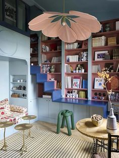 a living room filled with furniture and bookshelves next to a table covered in flowers