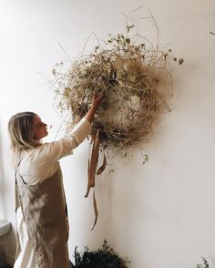 a woman is hanging plants on the wall