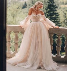 a woman in a wedding dress standing on a balcony with her hands on her hips