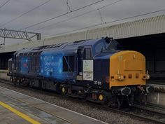 a blue and yellow train pulling into a station