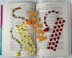 an open book with fruit and candy on the pages, including oranges, lemons, raspberries, and strawberries