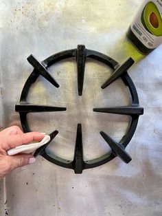 a person is using a bottle opener to make a circular design on a metal surface