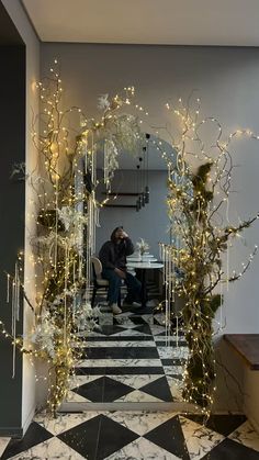 a man is sitting at a table in the middle of a room decorated with christmas lights