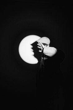 a woman standing in front of the moon with her hand on her face and looking up at it