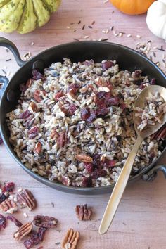 a bowl filled with rice and nuts on top of a table next to pumpkins