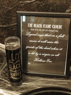 a black flam candle next to a sign on a table