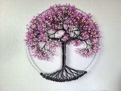 a metal tree with pink flowers on it is mounted to the wall in front of a white background