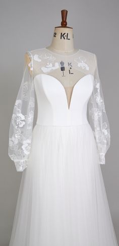 a white wedding dress with sheer sleeves and flowers