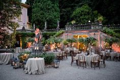 an outdoor dining area is lit up with candles and tables set for dinner outside at night