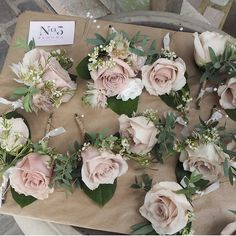 a table topped with lots of pink roses and greenery next to a price tag