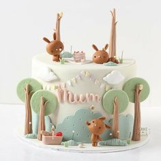 a cake decorated with animals and trees for a baby's first birthday