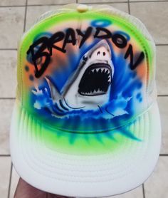 Custom made Trucker hat with your name and Shark...Perfect for any birthday party, event or just every day wear...one size adjustable back comes in a variety of hat colors, choose from list! If you would like to change the background colors, please message me with any 2 or 3 colors of your choice: (black is automatically included) Neon Pink, Neon Green, Neon Blue, Neon Orange, Red, Yellow, Blue, Green, Purple, Brown, Gray Spot clean with cold water, mild detergent...no bleach. Custom White Baseball Cap, Custom White Adjustable Baseball Cap, Themed Baseball Cap, Customizable Novelty Trucker Hat, Custom White Snapback Hat, Customizable Adjustable White Snapback Hat, Customizable Playful White Hats, White Themed Cap, Themed White Cap