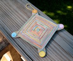 a crocheted cushion sitting on top of a wooden table next to a button