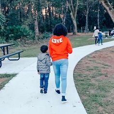 a woman and child walking down a path in the park