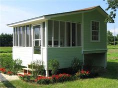 a small green house sitting on top of a lush green field