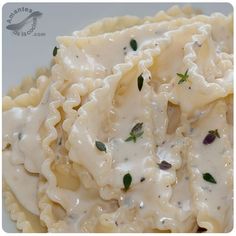 pasta with sauce and herbs on it in a white bowl