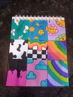 a spiral notebook covered in different colored squares with smiley faces and rainbows on them