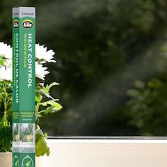 a white flower pot sitting on top of a window sill next to a plant