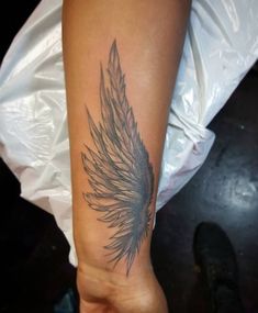 a woman's arm with a feather tattoo on it