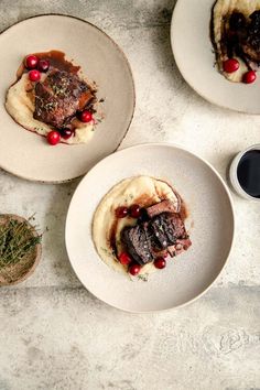 three white plates topped with meat and mashed potatoes