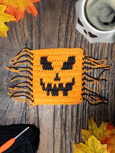 a crocheted pumpkin pattern next to a cup of coffee on a wooden table