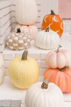 several pumpkins are sitting on the ledge in front of a white brick wall,