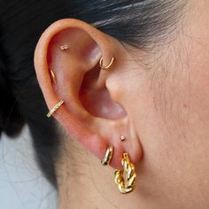 a close up of a person's ear with two gold rings on top of it