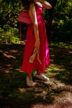 a woman in a red dress is talking on her cell phone and holding a pink purse