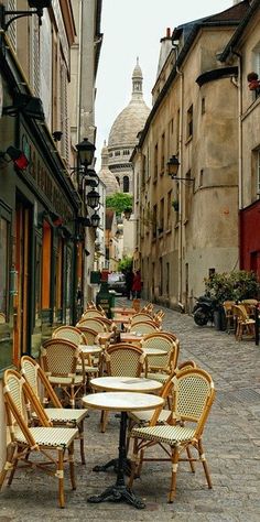 tables and chairs are lined up on the side walk in an old european city street